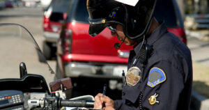 motorcycle police officer on a car stop as he writes a ticket